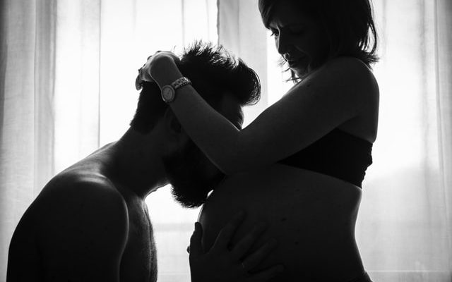 Pregnant woman, kissed on the belly by a man